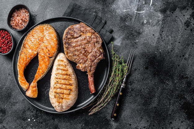 Bifes de carne grelhada peixe salmão vitela e filé de peru Fundo preto Vista superior Espaço para cópia