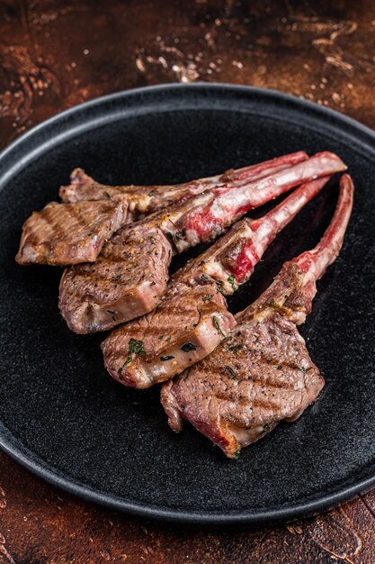 Bifes de costeletas de cordeiro grelhadas para churrasco em um prato Fundo escuro Vista superior