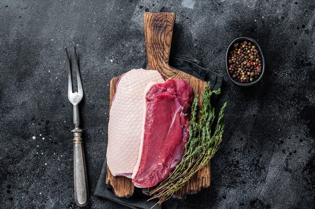 Bifes de filé de peito de pato, frango cru na tábua de madeira