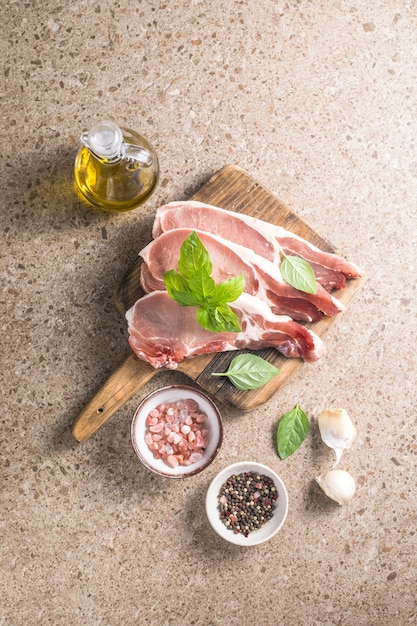 Bifes de porco cru com ervas de especiarias na tábua de cortar Carne fresca Vista superior espaço de cópia