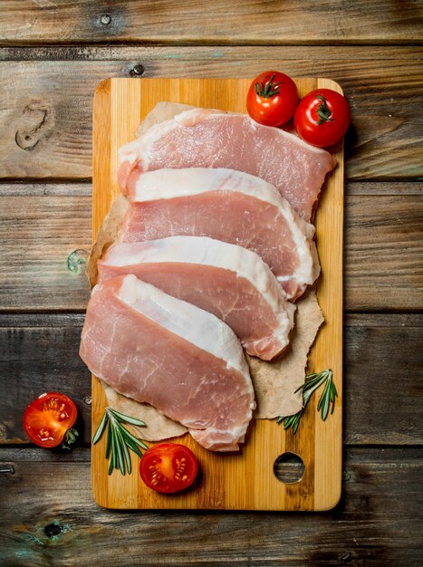 Foto bifes de porco cru com tomate e alecrim