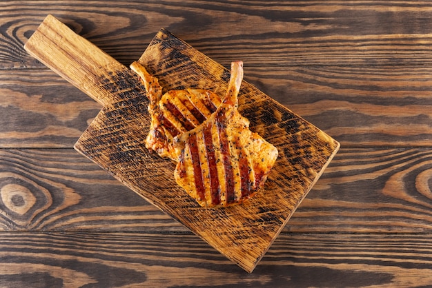 Bifes de porco grelhados com osso em mesa de madeira