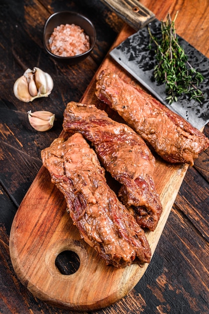 Bifes de saia marinados crus em molho de churrasco em uma tábua de madeira com ervas