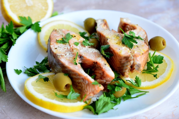 bifes de salmão assado com rodelas de limão, azeitonas e salsa picada no prato, macro