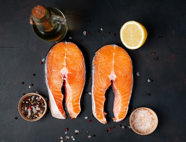 Bifes de salmão cru com especiarias, ervas, sal e limão em um fundo de pedra.