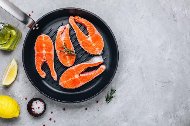 Bifes de salmão cru fresco com limão e alecrim em grelha no fundo cinza Espaço de cópia de vista superior