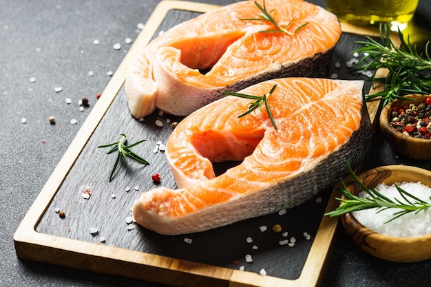 Bifes de salmão fresco de peixe salmão na tábua em fundo preto Vista superior com espaço de cópia