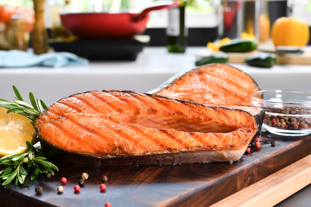 Bifes de salmão grelhados com ingredientes em uma tábua de madeira na cozinha
