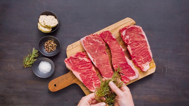 Bifes de tira crua de nova york em uma tábua de madeira.