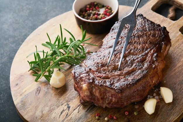 Bifes grelhados New York Steak com especiarias alecrim e pimenta na placa de mármore preto sobre fundo cinza Vista superior Mock up