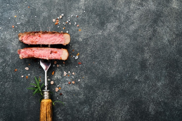 Bifes Tbone Fatias de bife de churrasco de carne grelhada no garfo de carne em fundo de madeira escuro queimado com espaço de cópia para o seu texto Vista superior Mock up