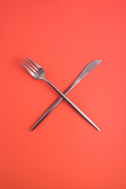 Bifurcaciones cruzadas y un cuchillo en un fondo anaranjado, un símbolo del abastecimiento, cafetería, restaurante.