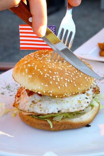 Big American Burger wird mit einem Messer geschnitten