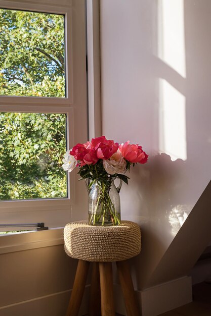 Big frische rosa und weiße Pfingstrose blühenden Blumenstrauß neben weißen Fenster auf einem grünen verschwommenen Baum und blauer Himmel Hintergrund Frühling Wohnkultur oder Geschenkidee Lebendige Sommerfarben