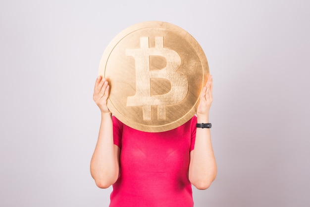 Big Golden Bitcoin in einer Frauenhand, digitales Symbol einer virtuellen Kryptowährung.