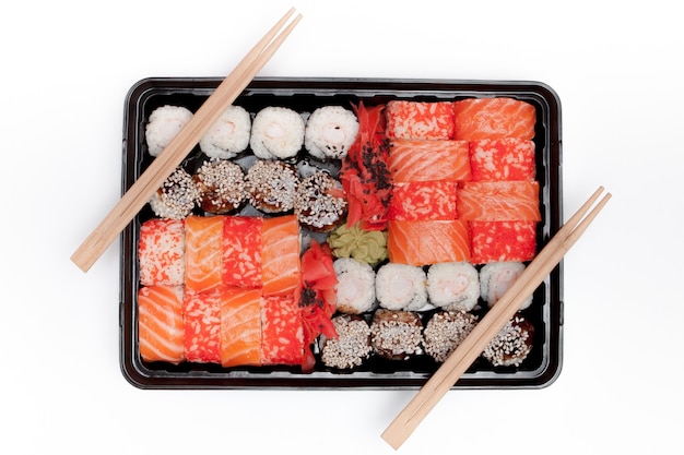Foto big sushi set ib caja de plástico negra sobre fondo blanco, vista superior de cerca, copie el espacio.