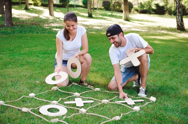 Foto big tic tac toe spiel. mann und mädchen spielen im freien.