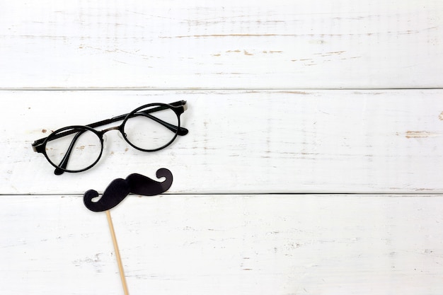 Bigotes de papel de la falsificación de la forma del corazón en fondo blanco de madera. Concepto feliz del día de padres.