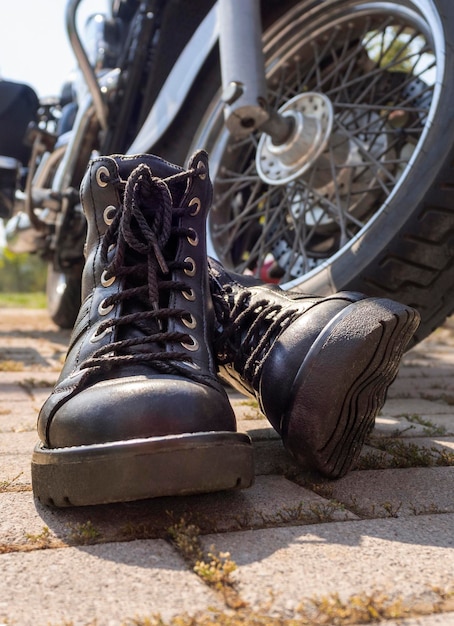 Foto biker botas con cordones closeup de pie cerca de la rueda de un helicóptero de motocicleta