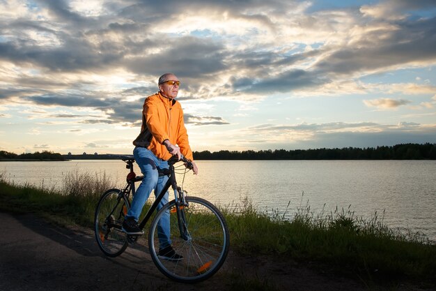 Biker se detuvo en el contexto de la puesta de sol en el lago