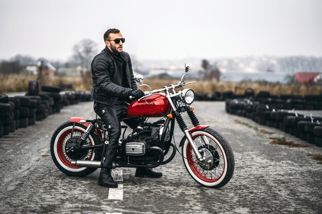 Foto biker em um terno de couro sentado em uma moto vermelha na estrada