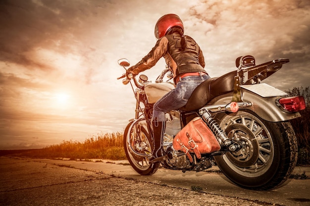 Biker girl en una chaqueta de cuero y casco en una motocicleta