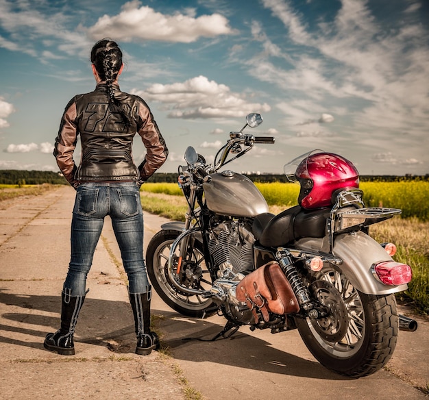 Biker girl en una chaqueta de cuero y casco en una motocicleta