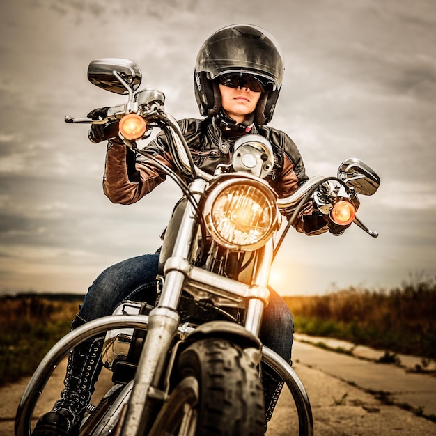 Biker girl en una chaqueta de cuero y casco en una motocicleta