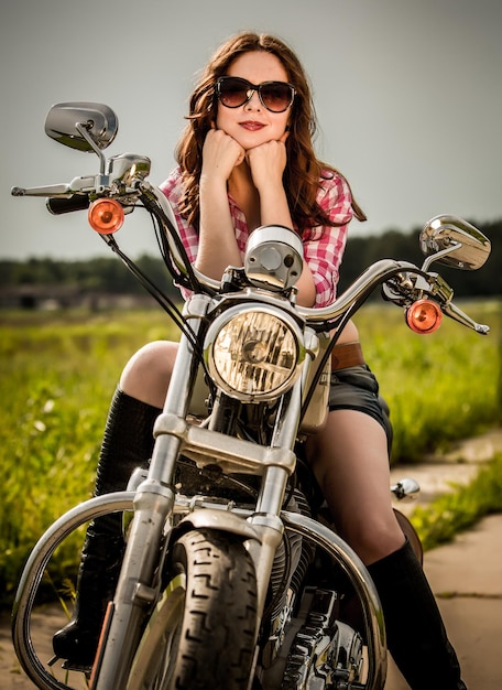 Biker Girl mit Sonnenbrille sitzt auf dem Motorrad