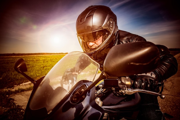 Biker in Helm und Lederjacke, die auf der Straße rennen. In der Postproduktion angewendeter Filter.