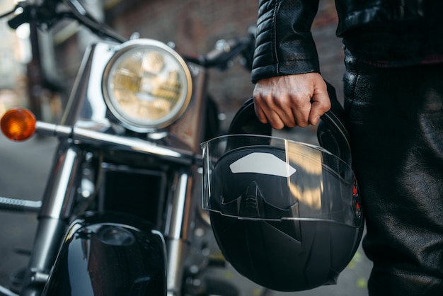 Biker in Lederjacke mit Helm in der Hand