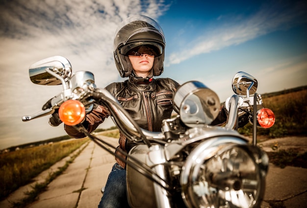 Biker-Mädchen in Lederjacke und Helm auf einem Motorrad