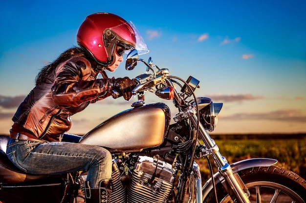 Biker-Mädchen in Lederjacke und Helm auf einem Motorrad