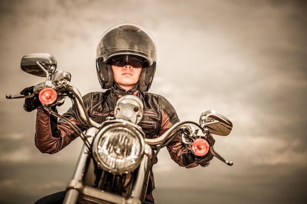 Biker-Mädchen in Lederjacke und Helm auf einem Motorrad