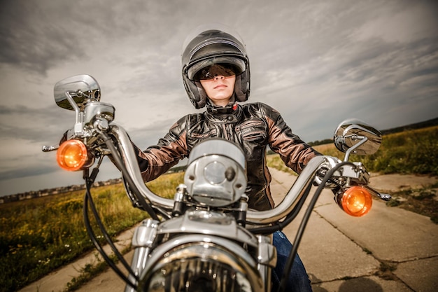 Foto biker-mädchen in lederjacke und helm auf einem motorrad