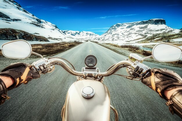 Biker monta una motocicleta en un camino resbaladizo a través de un paso de montaña en Noruega. Alrededor de la niebla y la nieve. Vista en primera persona.