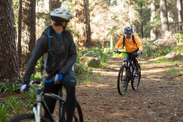 Biker pareja montando bicicleta de montaña en el bosque