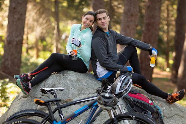 Biker pareja sentada en la roca en el bosque