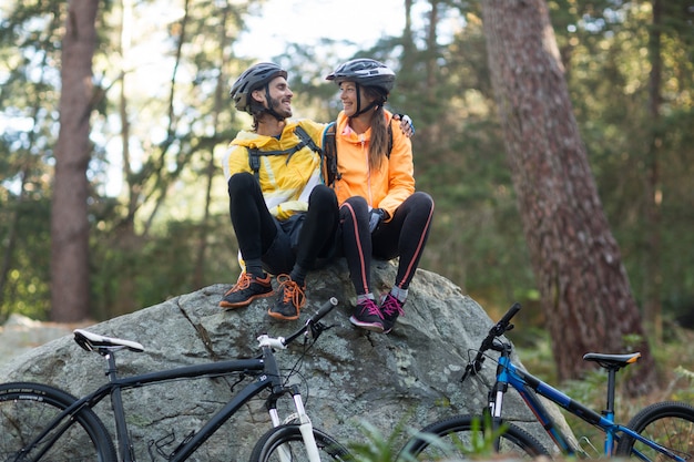 Biker pareja sentada en roca e interactuando entre sí