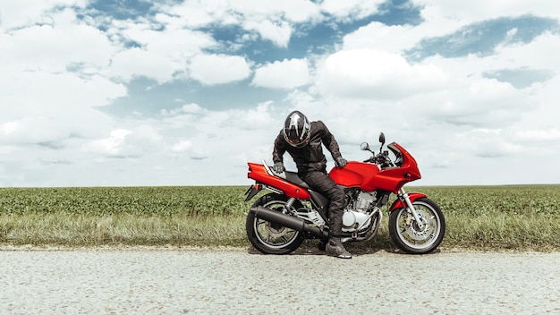 Foto biker sentado en una motocicleta mira la rueda trasera