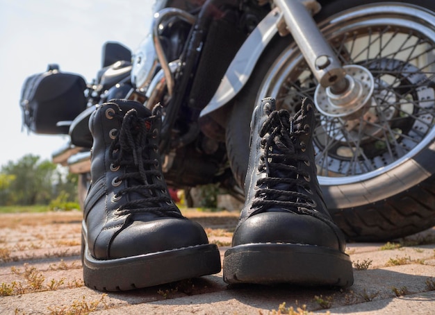 Biker-Stiefel mit Schnürsenkeln stehen in der Nähe des Rades eines Motorrad-Choppers