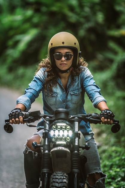 Bikerin, die ein Cafe Racer Motorrad fährt