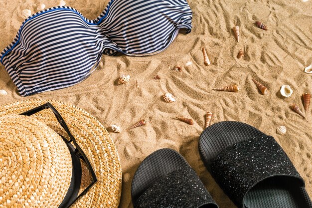 Bikini de verano y accesorios con estilo conjunto de playa, traje de verano de bikini de playa y arena de mar como fondo, vista superior, concepto