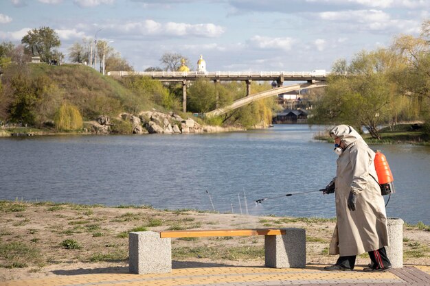 Bila Tserkva Ucrania 20 de abril de 2020 Un hombre con un abrigo gris trata el área con una solución de limpieza Tiendas contenedores de basura procesamiento de Covid19 La epidemia de Covid19 Pandemia Playa Río