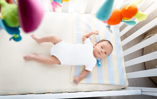 Bild aus hoher Sicht des kleinen Babys, das am sonnigen Tag in der weißen Wiege liegt