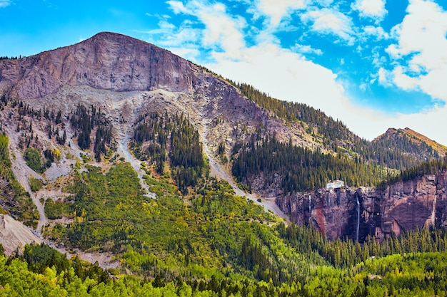 Bild der Ansicht eines großen Berges aus grauem Felsen, Espen und Kiefern