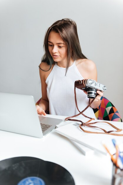 Bild der attraktiven zufälligen schönen Frau, die an einem Laptop arbeitet, der auf dem Stuhl im Haus sitzt.