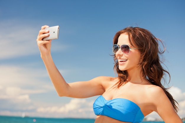 Bild der glücklichen Frau mit Telefon am Strand.