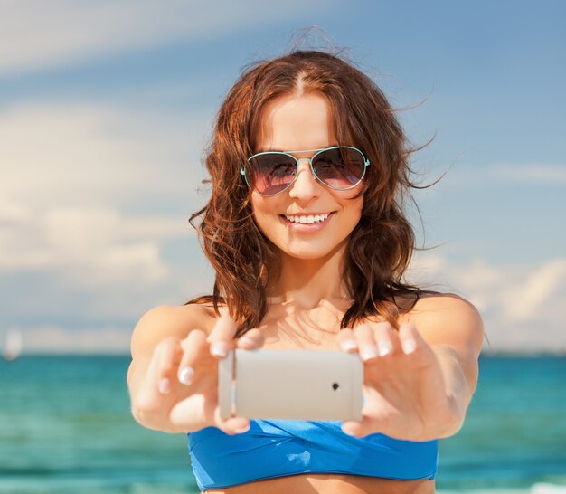 Bild der glücklichen Frau mit Telefon am Strand.