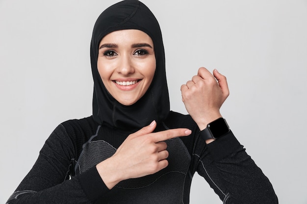 Bild der jungen Frau Fitness-Muslim mit Uhr isoliert.